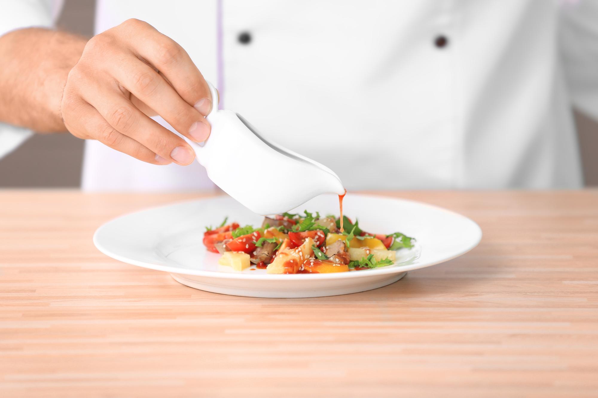 Chef arranging plated dish on wooden table